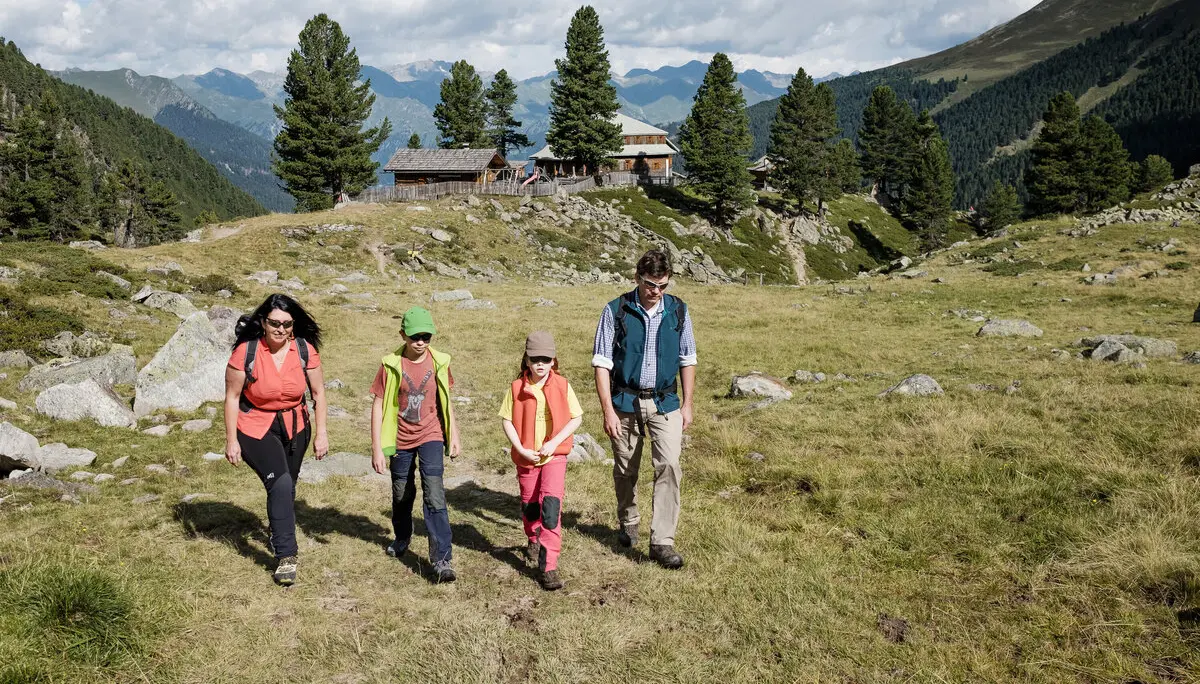 Eine Familie mit zwei kleinen Kindern wandert über eine Bergwiese | © DAV/Hans Herbig