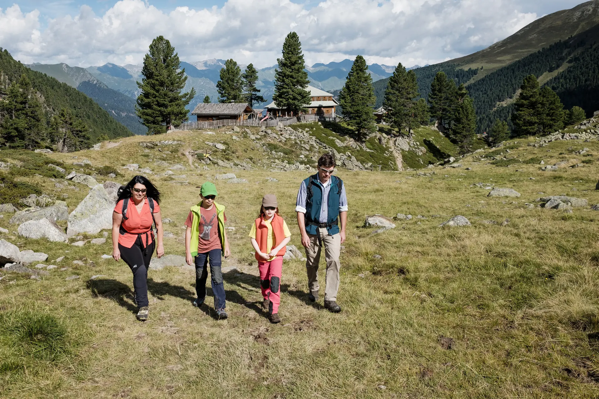 Eine Familie mit zwei kleinen Kindern wandert über eine Bergwiese | © DAV/Hans Herbig