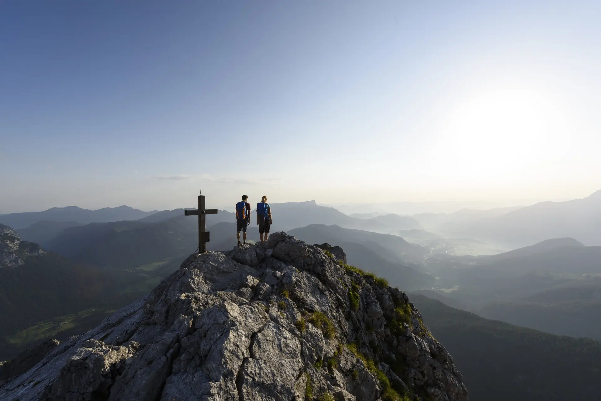 Zwei Wanderer auf einem Berggipfel mit Gipfelkreuz - aus der Ferne fotografiert | © DAV/Wolfgang Ehn